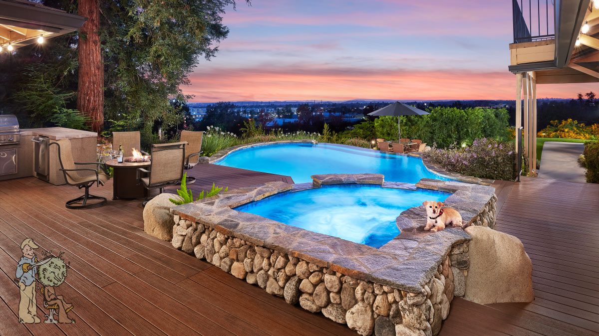 A backyard with a stone hot tub and pool at sunset, surrounded by a deck with seating and a grill; a dog is lying by the hot tub, and city lights are visible in the distance.